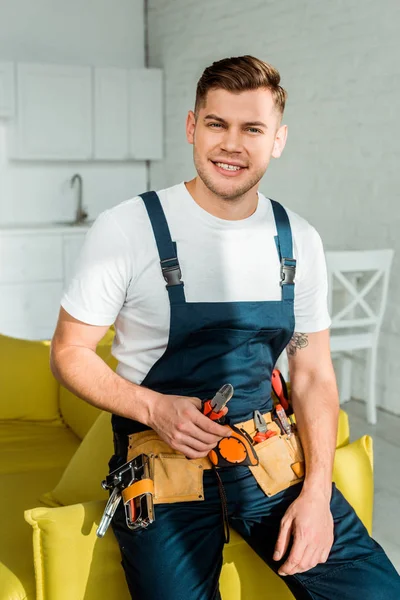 Sunshine on cheerful installer in overalls holding pliers — Stock Photo