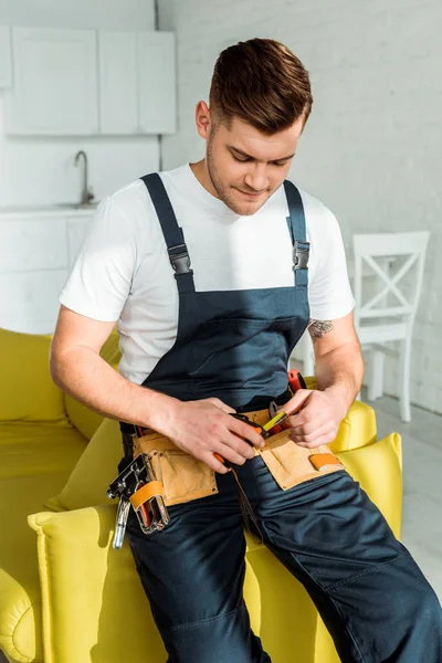 Sonnenschein auf gutaussehendem Installateur in Latzhose mit Maßband — Stockfoto