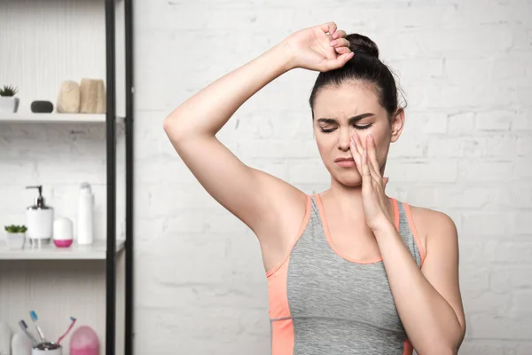 Displeased woman plugging nose with hand while looking at underarm — Stock Photo