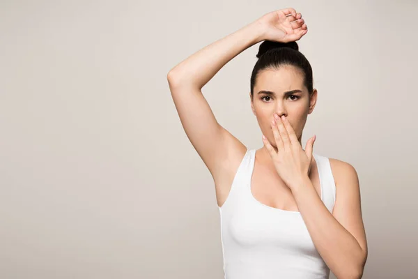 Shocked woman covering mouth with hand while looking at camera isolated on grey — Stock Photo