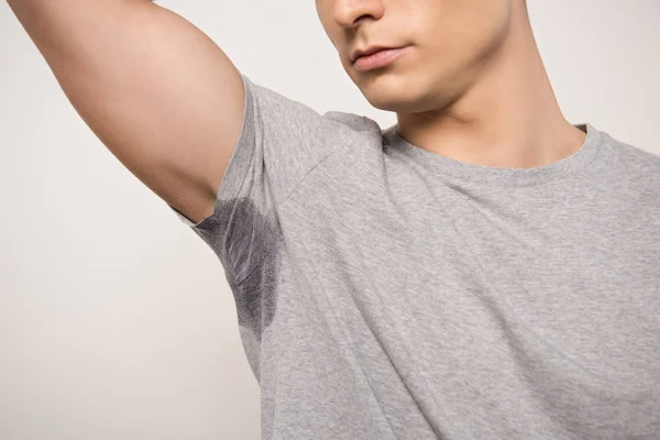 Vista cortada de homem jovem em camiseta cinza com a axila suada isolada em cinza — Fotografia de Stock