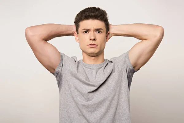 Shocked man in grey t-shirt with sweaty underarms looking at camera isolated on grey — Stock Photo