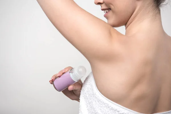 Cropped view of smiling woman applying deodorant on underarm isolated on grey — Stock Photo