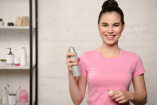 Mujer feliz sonriendo a la cámara mientras sostiene el desodorante - foto de stock