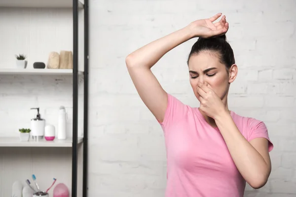 Schockierte Frau verstopft Nase mit der Hand beim Blick auf Achselhöhlen — Stockfoto