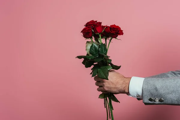 Vista cortada do homem segurando buquê de rosas vermelhas, isolado em rosa — Fotografia de Stock