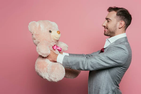 Homem alegre em terno segurando ursinho de pelúcia em rosa — Fotografia de Stock
