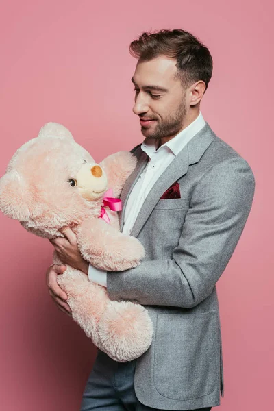 Felice uomo barbuto in abito che tiene orsacchiotto su rosa — Foto stock