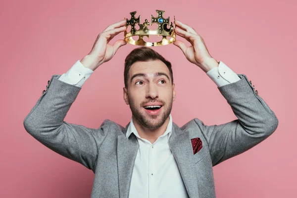 Happy emotional bearded man wearing crown and suit, isolated on pink — Stock Photo
