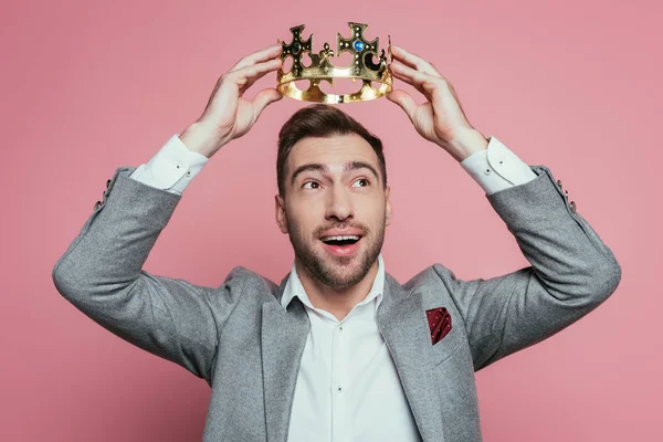 Homem barbudo emocional feliz vestindo coroa e terno, isolado em rosa — Fotografia de Stock