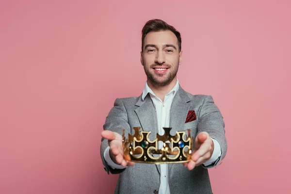 Smiling bearded man in suit holding crown, isolated on pink — Stock Photo