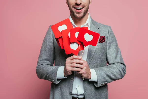 Vista cortada de homem segurando cartões com corações para dia dos namorados, isolado em rosa — Fotografia de Stock