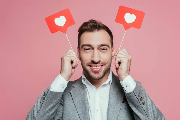 Sonriente hombre sosteniendo tarjetas con corazones para el día de San Valentín, aislado en rosa - foto de stock