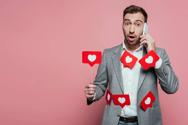 Bell'uomo che parla su smartphone e tiene le carte con i cuori per San Valentino, isolato su rosa — Foto stock