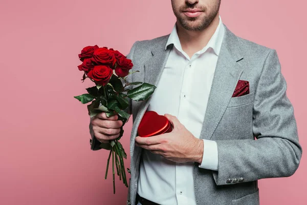 Vista ritagliata di uomo in possesso di scatola regalo cuore e mazzo di rose per San Valentino, isolato su rosa — Foto stock