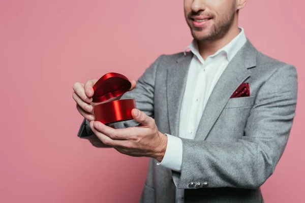 Vista cortada do homem segurando caixa de presente do coração para o dia dos namorados, isolado no rosa — Fotografia de Stock