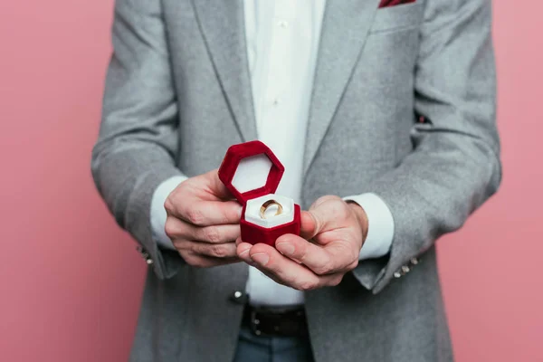 Corte vista de homem em terno segurando caixa com anel de proposta, isolado em rosa — Fotografia de Stock