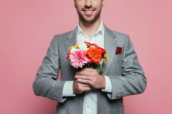 Vista ritagliata di uomo felice che tiene mazzo di fiori, isolato su rosa — Foto stock