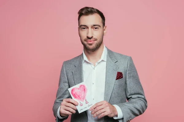 Homem barbudo segurando cartão de Dia dos Namorados com coração, isolado em rosa — Fotografia de Stock