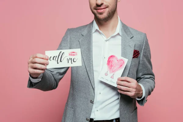 Cropped view of man holding two valentines day cards, isolated on pink — Stock Photo