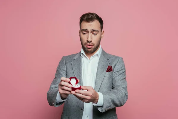 Upset man holding box with proposal ring, isolated on pink — Stock Photo