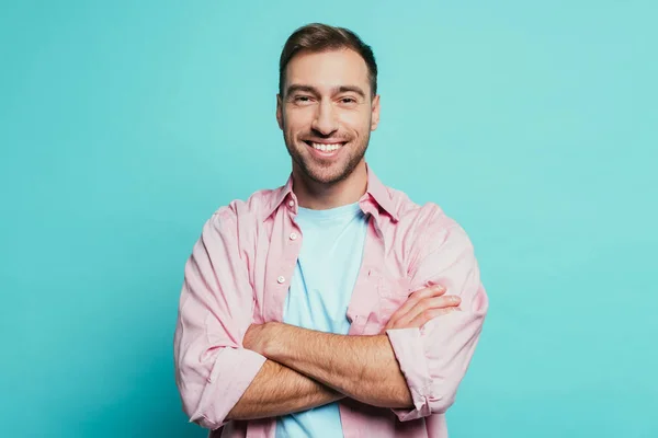 Bell'uomo sorridente con le braccia incrociate, isolato sul blu — Foto stock