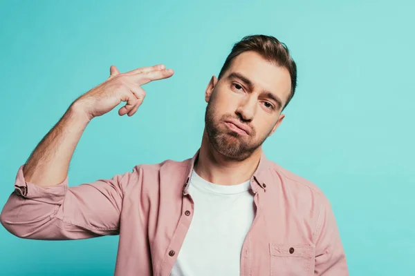 Confused man with hand gun gesture, isolated on blue — Stock Photo