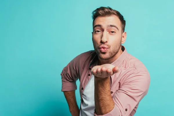 Smiling handsome man blowing air kiss isolated on blue — Stock Photo