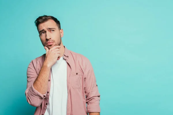 Thoughtful handsome man gesturing and looking up, isolated on blue — Stock Photo