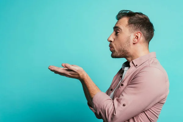 Felice bello uomo soffiando aria bacio isolato su blu — Foto stock