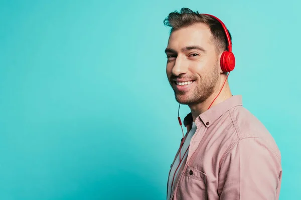 Усміхнений бородатий чоловік слухає музику з навушниками, ізольований на синьому — стокове фото
