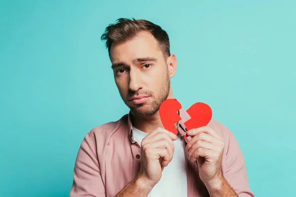 Uomo sconvolto tenendo il cuore spezzato, isolato sul blu — Foto stock