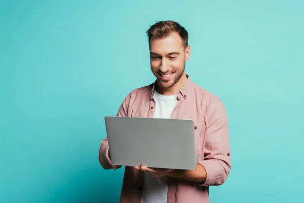 Allegro uomo barbuto utilizzando il computer portatile, isolato su blu — Foto stock