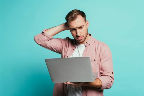 Bearded pensive man using laptop, isolated on blue — Stock Photo