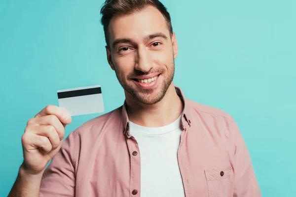 Счастливый бородатый мужчина, держащий кредитную карту, изолированный на голубом фоне — стоковое фото