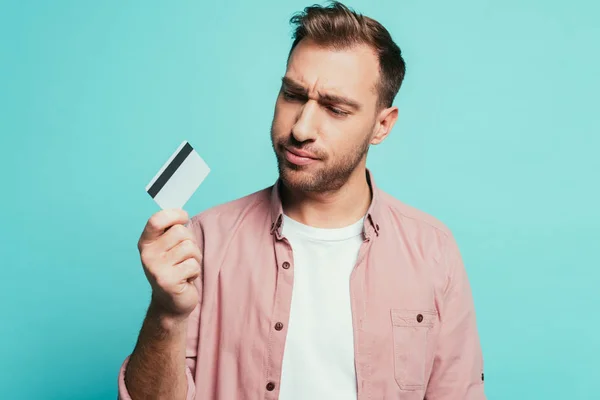 Uomo frustrato in possesso di carta di credito, isolato su blu — Foto stock