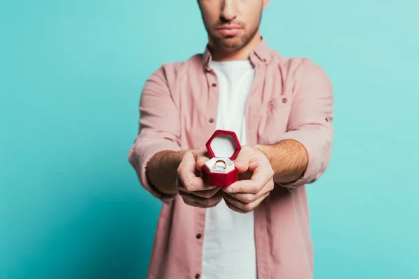 Vista cortada de homem sério segurando caixa com anel de proposta, isolado em azul — Fotografia de Stock