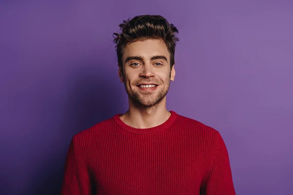 Joven, hombre guapo sonriendo a la cámara sobre fondo púrpura - foto de stock