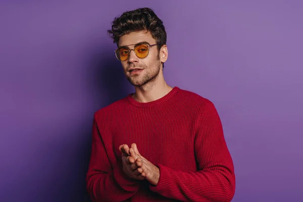 Thoughtful man rubbing hands while looking away on purple background — Stock Photo