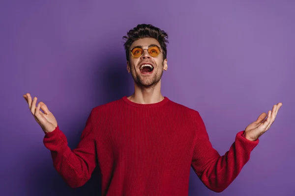 Happy man looking up while standing with open arms on purple background — Stock Photo