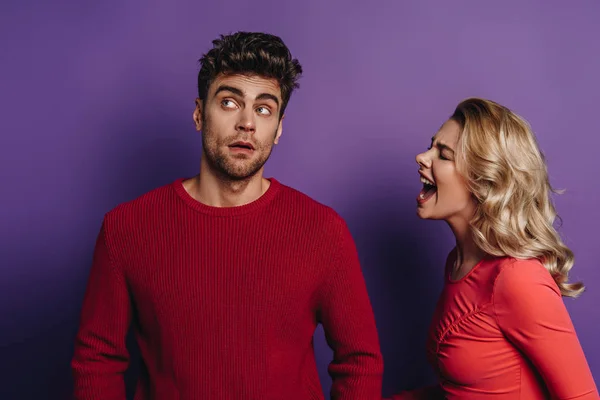 Irritated girl screaming at boyfriend looking away on purple background — Stock Photo