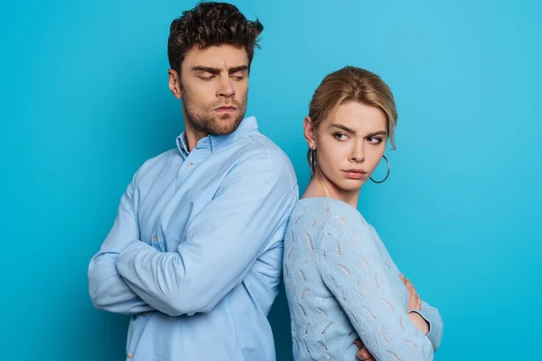 Ofendido homem e mulher de pé de volta para trás com os braços cruzados no fundo azul — Fotografia de Stock