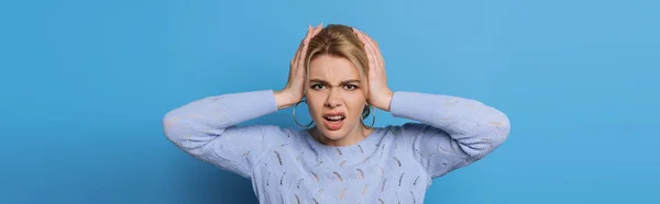 Panoramic shot of displeased girl touching head while suffering from migraine on blue background — Stock Photo