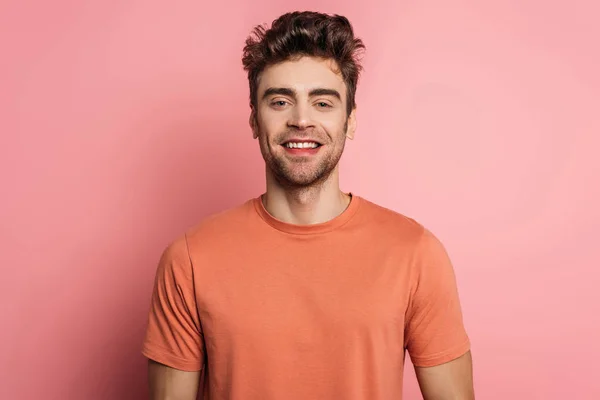 Красивий, щасливий чоловік посміхається на камеру на рожевому фоні — стокове фото