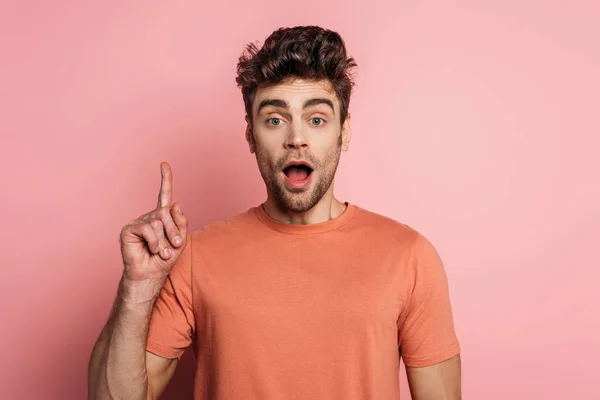 Shocked man showing idea sign while looking at camera on pink background — Stock Photo