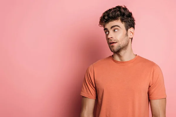 Schöner, verträumter Mann, der auf rosa Hintergrund wegschaut — Stockfoto