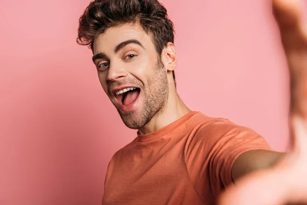 Excited man taking selfie while looking at camera on pink background — Stock Photo