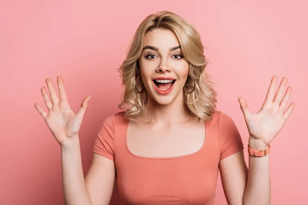 Cheerful girl waving hands while smiling at camera on pink background — Stock Photo