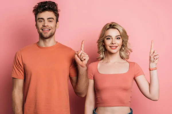 Positiver Mann und Frau, die Ideenschilder zeigen, während sie in die Kamera auf rosa Hintergrund schauen — Stockfoto