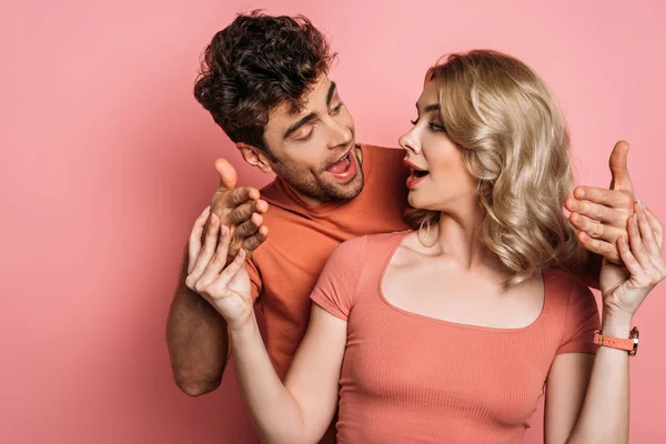 Attractive girl stopping boyfriend trying to touch her on pink background — Stock Photo